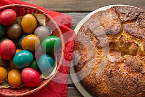 Top view of a Kozunak Traditional Easter sweet bulgarian bread and colored eggs in a red wicker basket