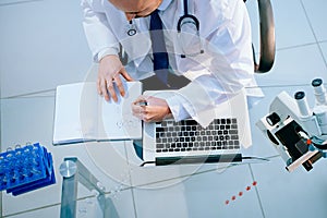 top view. lab scientist using a laptop to save data.