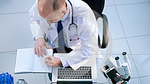 top view. lab scientist using a laptop to save data.