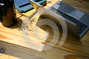 Top view of a laptop computer, books and decor on a wooden tabletop