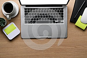 Top view of laptop computer, coffee cup, sticky note and cactus on wooden table.