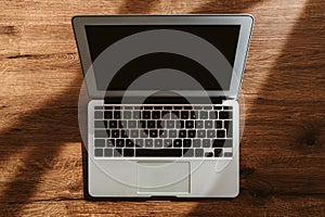 Top view of laptop computer on office desk with blank black mockup screen and copy space