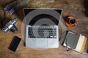 Top view of laptop, diary, vintage photo camera and cup of coffee