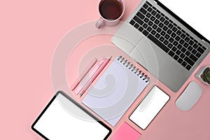 Top view laptop, digital tablet, smart phone, glasses and coffee cup on pink background.