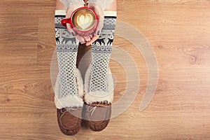 Top view of laptop in girl`s hands sitting on a wooden floor with cup of coffee, christmas decoration, gifts and wrapping paper