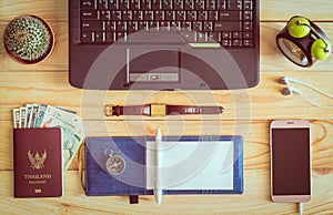 Top view of laptop, notebook, pen, passport, money, mobile phone