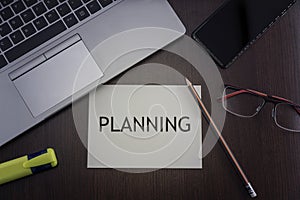 Top view of laptop, phone, glasses and pencil with card with inscription planning