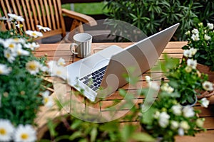 Top view of laptop on table on balcony in summer, outdoors office concept.