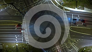 Top view of large multilane road intersection with traffic lights and moving cars and trucks at night. Timelapse of