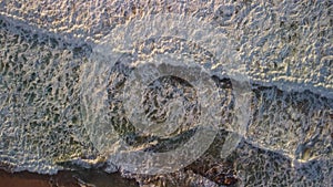 Top view of large waves with sea foam, sunset.