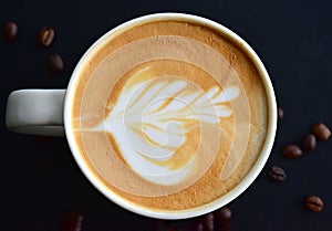 Top view of latte art ,on the dark wood table have many coffee beans