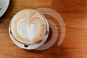Top view of Latte art heart shape served in clear glass with woonden table in the background