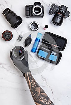 Top view layout of cleaning workstation for photography cameras and a man hand holding a camera lens