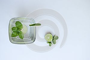 Top view of lemon and mint detox drink in a glass against white background