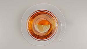 TOP VIEW: Lemon slice swims in a black tea in a glass tea cup on a table