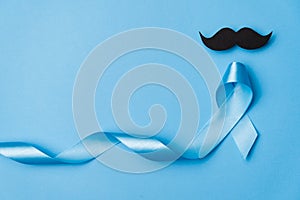 Top view on Light blue ribbon with mustache on blue background . Prostate Cancer Awareness,creative solution