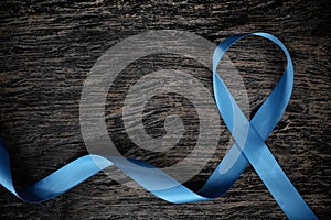 Top view of light blue ribbon on wooden background with copy space. Men`s health and prostate cancer awareness and concept.