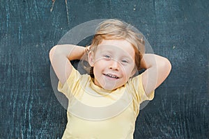 Top view of a little blond kid boy with space for text and symbols on the old wooden background. Concept for confusion, brainstorm