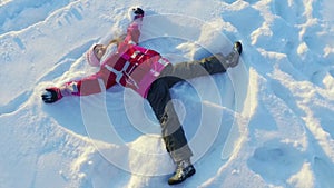 Top view little girl making snow angel. Winter kid. Sunny winter day