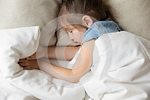 Top view of little girl sleeping in cozy home bed