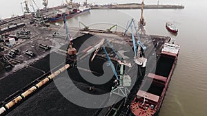 Top view of the loading of coal by tower cranes into tankers on the territory of the seaport and floating ships in the