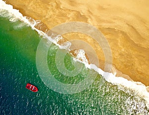 Top view of a lonely red boat anchored off the coast of ocean beach