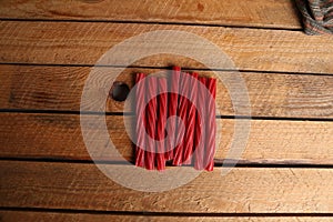 Top view of long red twisted candies abreast on a wooden table
