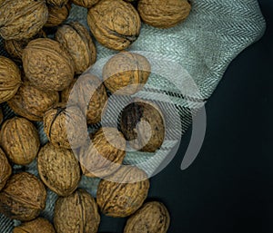 Top view of a lot of walnuts on kitchen cloth, black background, healthy food concept
