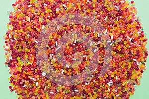 Top view of lots of bright colorful plastic beads on light green background