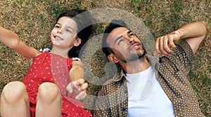 Top view of loving father has outdoors activity with his daughter lying on the grass looking up to the sky, searching for an