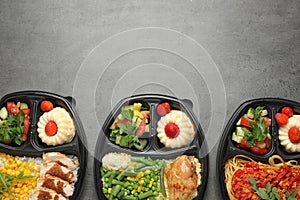 Top view of lunchboxes with different meals on grey table. Healthy food delivery