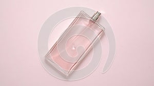 Top view of luxury bottle of perfume on pastel pink surface. Minimal composition. Flat lay