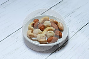 Top view of macadamia,cashew,almond and peanuts nuts in bowl on wooden background.