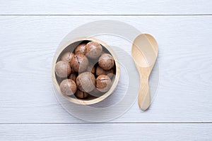 Top view macadamia in wooden bowl on white wooden table