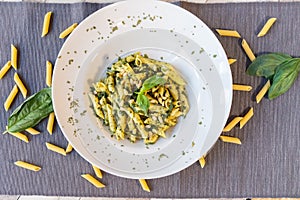 Top view of macaroni basil pesto plate with parmesan cheese and pinions