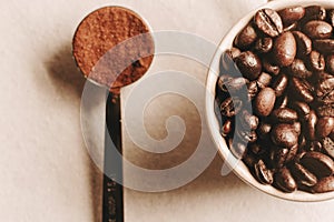 Top view, macro shot of coffee cup full of coffee beans and coffee ground in tiny spoon