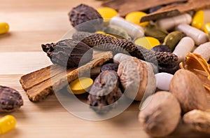 Top view macro shot of herbal pills and tablets arranged with spices on a red stone. Unani medicines concept