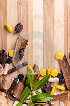Top view macro shot of herbal pills and tablets arranged with spices on a red stone. Unani medicines concept