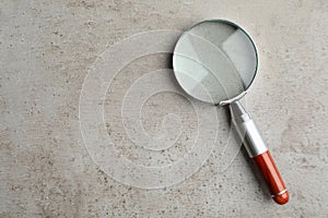 Top view of magnifier glass on grey stone background, space for text. Find keywords concept