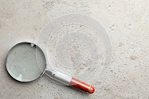 Top view of magnifier glass on light grey stone background, space for text. Find keywords concept