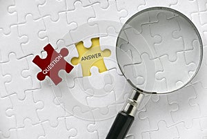 Top view of magnifying glass, and a jigsaw puzzle written with Question and Answer