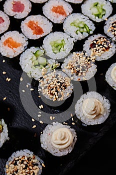 Top view Maki rolls lie on a black stone sushi board.