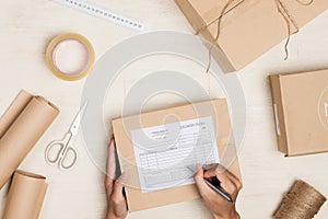 Top view of making notes in delivery receipt among parcels at table