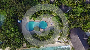 Top view of Maldives island, camera is rising over the swimming pool on luxury hotel. Aerial video of resort with lots