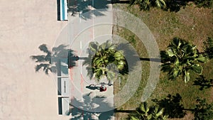Top view of male driving electric scooter among tropical summer palm trees with shadows along the promenade. Ecological