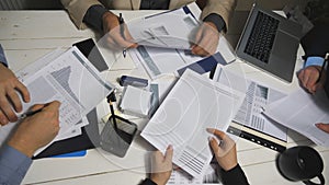 Top view male and female hands of colleagues analyzing financial reports in office. Business team sitting at table and