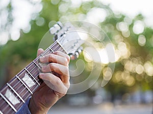 A top view on male hand plays guitar in a jeans jacket in a park on a blurred background. photo