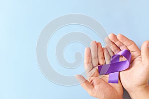 Top view of male hands holding purple ribbon color. Testicular, pancreatic cancer, epilepsy, leiomyosarcoma, lupus, Alzheimer`s photo