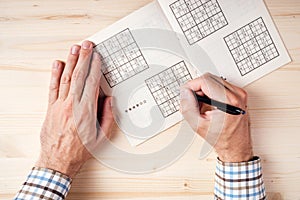 Top view of male hands solving sudoku puzzle