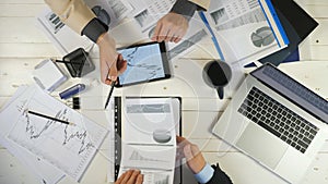 Top view male hands of two young businessmen checking graphs and discussing financial reports in office. Successful